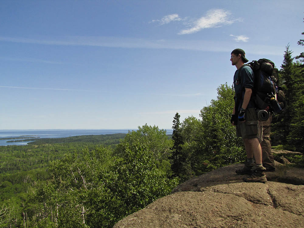 Man standing on rocky outcrop looking over Lake Superior on Isle Royale.
