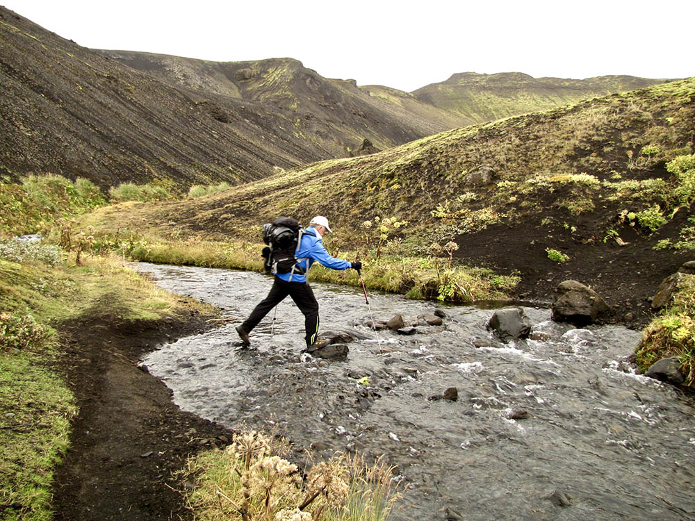 Backpacker crossing stream in Iceland's Laugavegur Trail.
