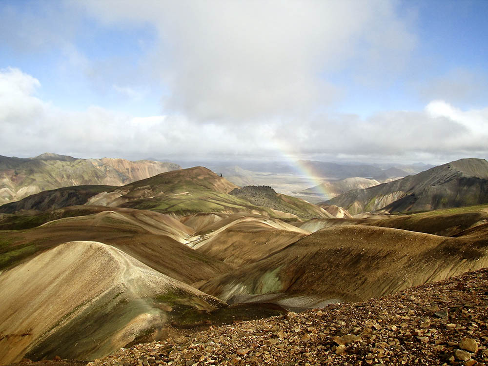 Vista of brown and tan hills and a rainbow, seen along Iceland's Laugavegur Trail.