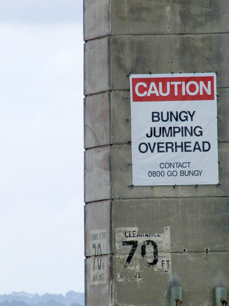 Sign saying, "Caution: Bungy Jumping Overhead," in New Zealand, home of extreme sports.