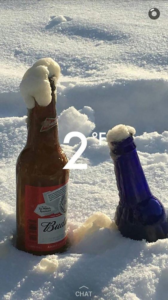 Two bottles of beer in the snow with frozen beer coming out of them and a notation that it's 2 degrees, taken during the Snowshoe Beer Mile.