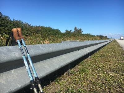 Trekking poles leaning against guardrail along highway.