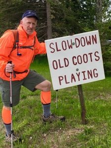 Hiker in orange standing by sign saying, 