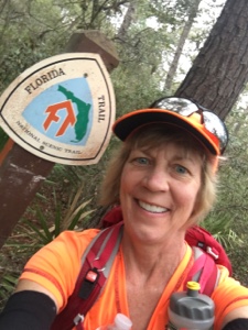 Backpacker standing next to a Florida Trail signpost.