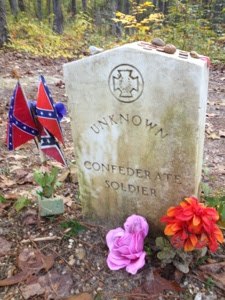 Tombstone with plastic flowers and two Confederate flags in front of it along the Natchez Trace.