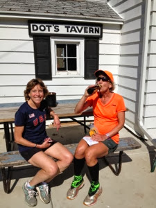 Two women sitting at a picnic table in front of a white building named Dot's Tavern near Brooklyn Wildlife on the Ice Age Trail.