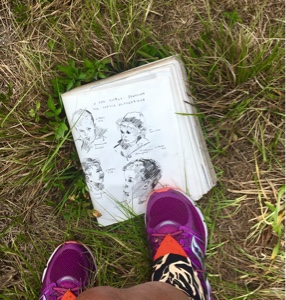 Woman's foot on sketch book laying in grass.