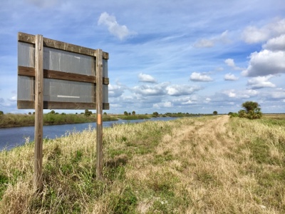View of Florida hiking trail on levee next to river.