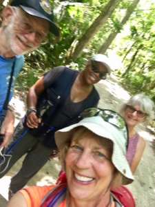 Three female hikers and one male taking a selfie on a trail.