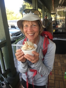 Female backpacker holding a dish of ice cream in her hands and smiling at the camera.