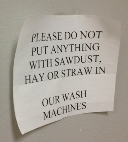 Sign on wall asking people not to put anything with sawdust, hay or straw into the washing machines.