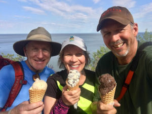 Three people holding ice cream cones with Lake Superior in the background.