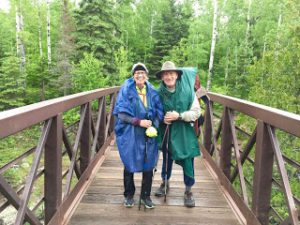 Two backpackers standing on a bridge in rain ponchos in Gooseberry Falls.