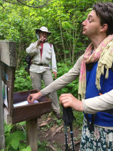 Two male hikers, part of hiking boom, signing trail log.