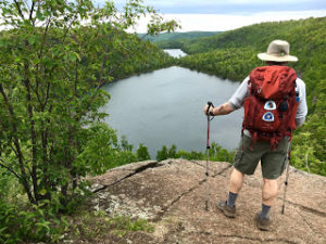 Backpacker standing on rocky outcrop near Bear and Bean Lakes on the Superior Hiking Trail near Penn Blvd