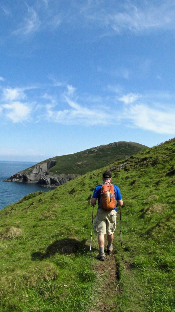 Man hikes atop bluffs along the sea on Wales Coast Path.