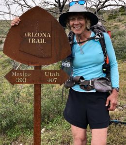 Female backpacker by Arizona Trail sign on her half-hike day.