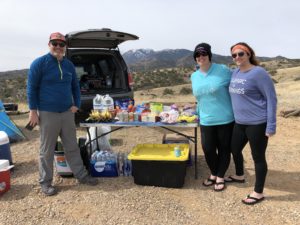 Three trail angels standing by a table full of food and drinks for hikers en route to FR 4062 on the Arizona Trail.