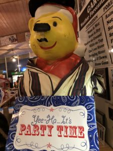 Statue of a bear with clothing on holding a sign saying "Yee-Ho It's Party Time" in Kearny on the Arizona Trail.