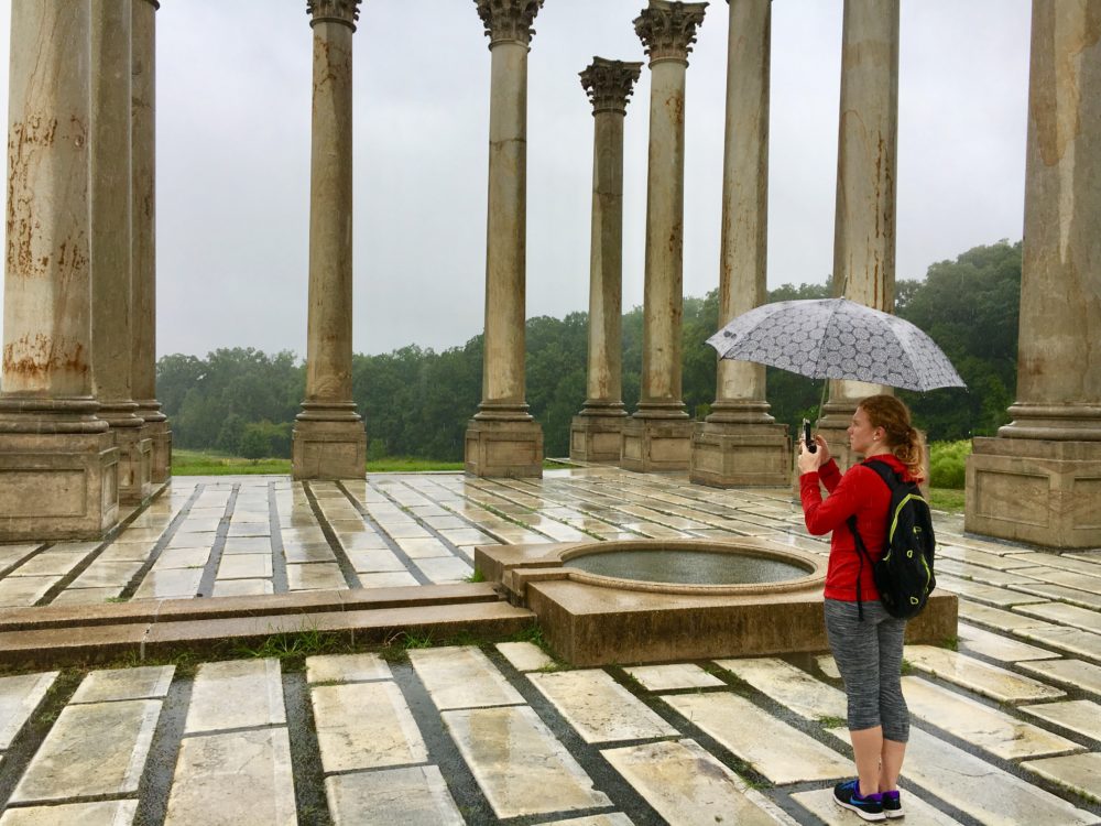 Woman standing with umbrella in the rain viewing the Capitol columns at the National Arboretum in Washington, DC.