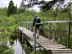 Man walking across bridge in Border Route Trail, which runs through the Boundary Waters Canoe Area Wilderness.