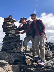 Male and female backpackers by stone cairn on top of a mountain