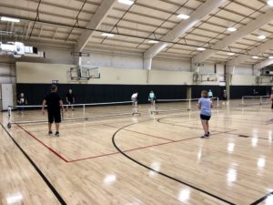 A group of people playing Pickleball on an indoor court