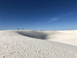 Hikers hiking on enormous white gypsum dunes at White Sands National Monument