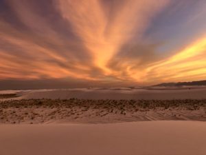 Setting sun at White Sands colors the sky and sand dunes yellow and orange.