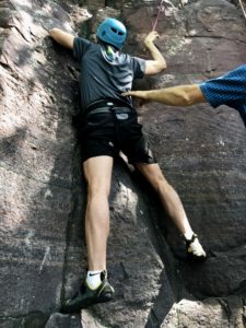 Man rock climbing with a hand reaching out to steady him