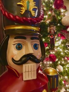 Giant nutcracker in front of Christmas tree.