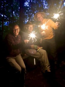 Three people holding sparklers in the dark at Pictured Rocks near Mosquito River.