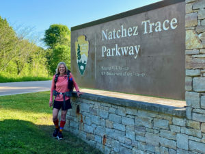 Woman standing by Natchez Trace Parkway sign, headed for Potkopinu section.