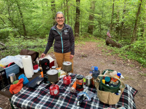 Woman hiker by a picnic table full of food near Ballard Creek on the Natchez Trace.