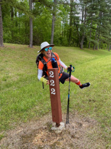 Female hiker standing by mile post 222 on the Natchez Trace.
