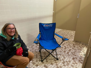 Woman sitting in camp chair in public restroom near the Tennessee-Alabama state line on the Natchez Trace.