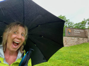 Woman holding umbrella near sign for Natchez Trace Parkway.