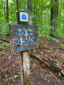 Sign on North Country Trail marking the 45-degree parallel near Jordan River and Pinney Bridge.