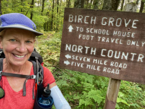 Female hiker standing in front of North Country Trail sign.
