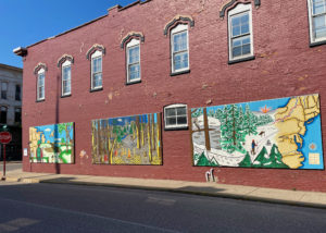 Red brick building with paintings of the North Country Trail on its side.