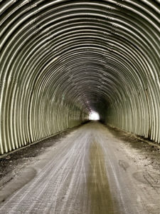 Inside of a tunnel reminiscent of a giant, steel culvert.
