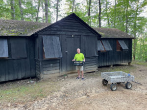 Man standing in front of old, weathered CCC cabin.
