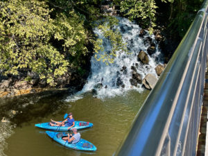 View of waterfall from a bridge with two kayaks underneath.