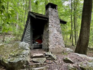 Old Appalachian Trail shelter with stone fireplace in the woods.