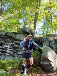 Female backpacker standing by huge rocks in the woods.