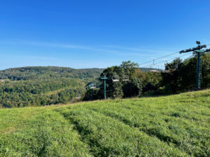Ski lift in the fall, with green grass and green hills in the distance.