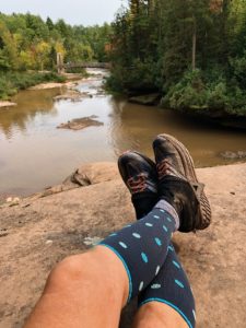 Pair of legs in compression sleeves on top of a rock; holiday gifts.