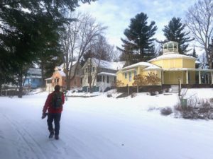Man walking in snow past pastel homes in Bay View.