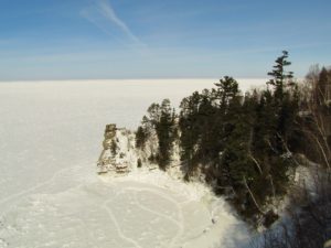 Frozen and snow-covered Lake Superior with rock formations.