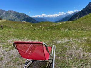 Red lounge chair in the grass in the mountains.